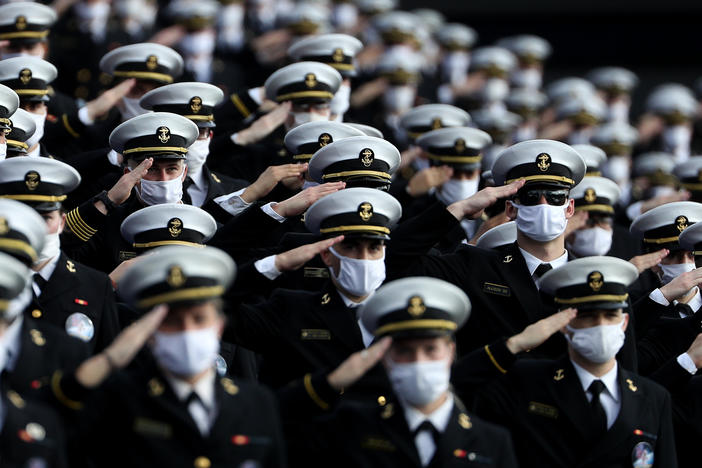 Midshipmen wearing face masks stand and salute before the Navy Midshipmen play against the Houston Cougars on Saturday in Annapolis, Md. Researchers have tried to estimate how many lives would be saved by universal mask-wearing.