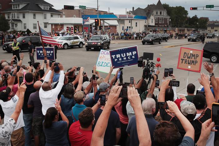Trump supporters and Trump protesters watch a passing motorcade carrying the president last month in Kenosha, Wis.