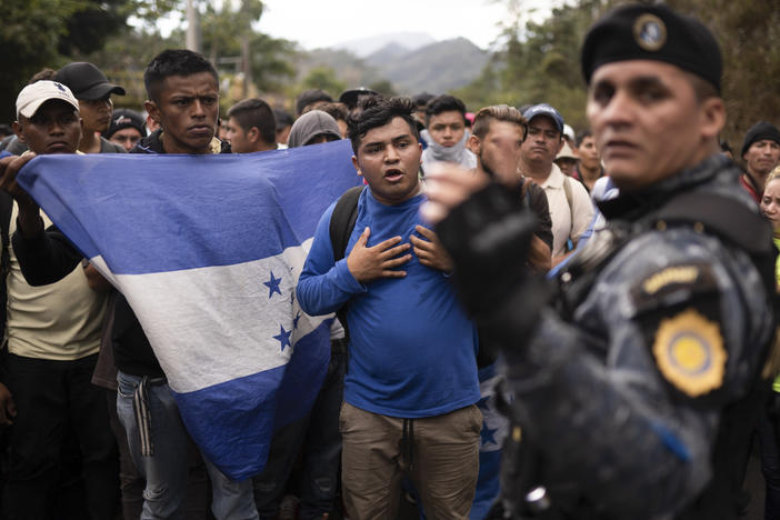 Honduran migrants walking in a group stop before Guatemalan police in January near Agua Caliente, Guatemala. The Democratic staff of the Senate Foreign Relations Committee says U.S. immigration agents in Guatemala helped officials deport Hondurans traveling in a migrant caravan earlier this year.