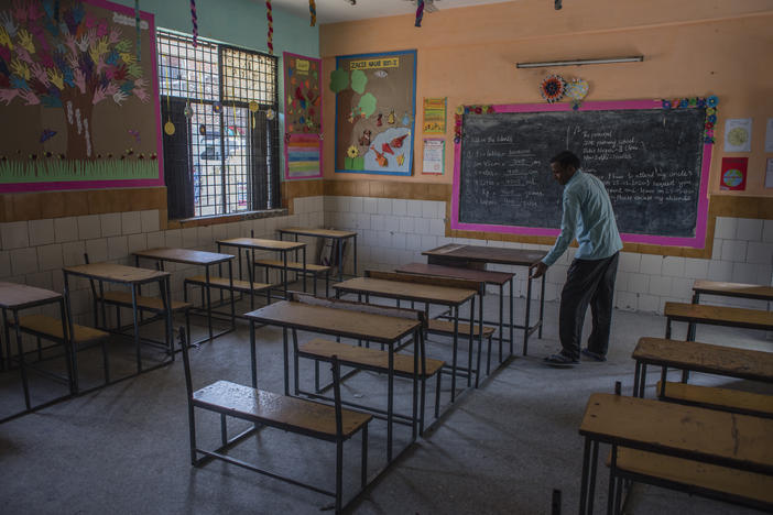 An employee adjusts desks in an empty classroom in New Delhi after schools there were closed in March. A new report finds 1 in 4 countries have either missed their planned school reopening date, or not yet set one.