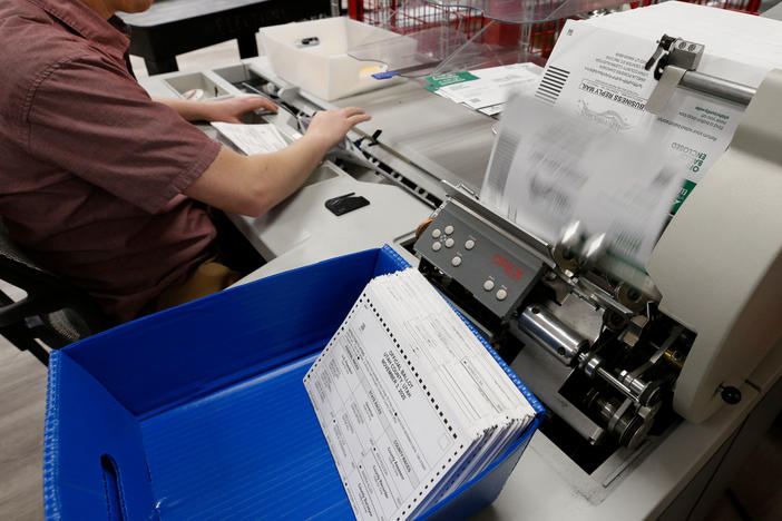 An election worker opens envelopes and removes ballots so they can be counted at the election office on Octo. 26, 2020 in Provo, Utah.