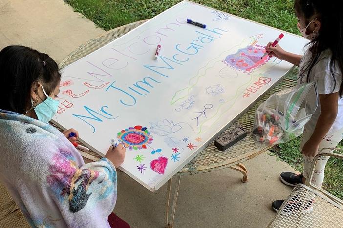 Nicole, a kindergartner, and Angelique, a third grader, make a poster welcoming a regular visitor to the learning hub who teaches the children how to care for their pets: Persephone the guinea pig and George Kiwi the turtle.