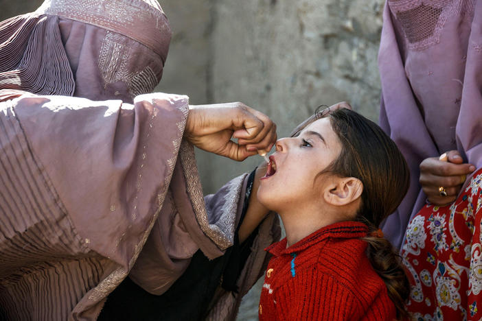 A health worker administers a polio vaccine to a child in Afghanistan's Kandahar province. Taliban opposition to vaccine campaigns have left millions of children unprotected against the virus.