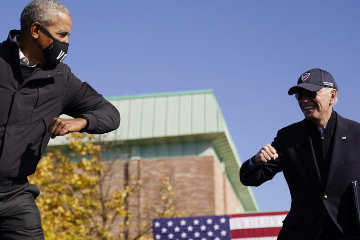 Democratic presidential nominee Joe Biden and former President Barack Obama greet each other at a drive-in rally in Flint, Mich.