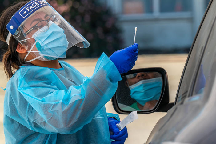 A medical worker administers a rapid COVID-19 test in Oakland, Calif., earlier this month. Coronavirus cases are once again surging across much of the country, reaching almost 100,000 on Friday.