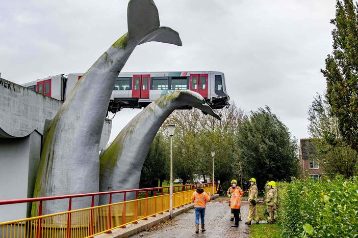 A massive sculpture of a whale's tail keeps a metro train aloft Monday after it shot through a stop block at De Akkers station in Spijkenisse, Netherlands. No injuries were reported.