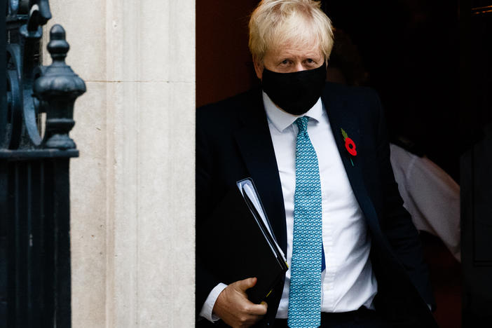 British Prime Minister Boris Johnson wears a mask and remembrance poppy as he leaves No. 10 Downing St. heading for the Houses of Parliament in London after ordering a new England-wide coronavirus lockdown.