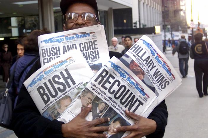 A man holds four copies of the Chicago Sun-Times, each with a different headline, on Nov. 8, 2000.