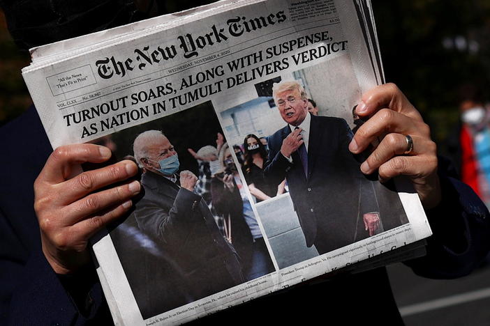 A man holds a fresh copy of <em>The New York Times</em> on Wednesday morning on Black Lives Matter Plaza near the White House.