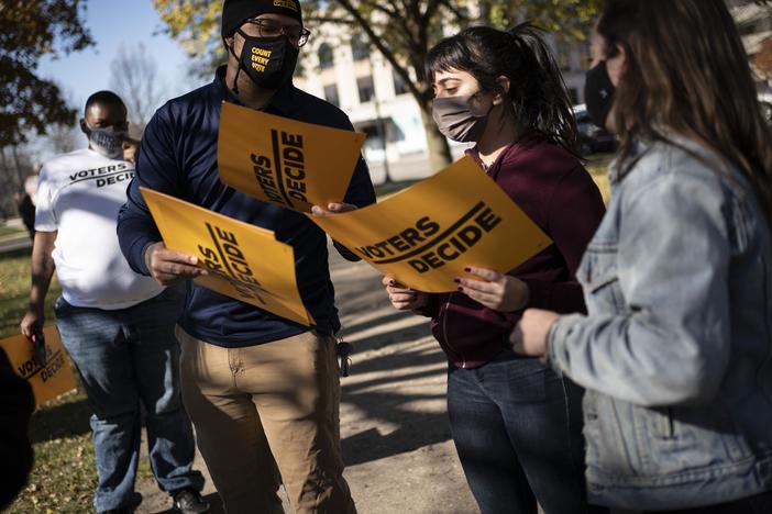 People gather with signs that read "Voters Decide" at the Civic Center Park while waiting for the results of election in Kenosha, Wis., on Wednesday.