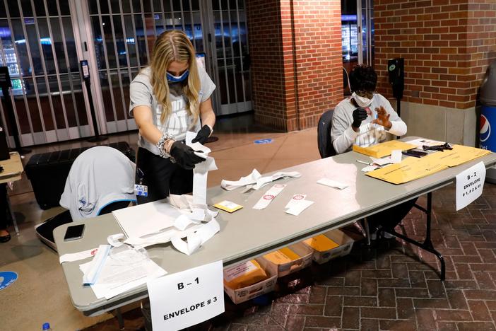 Election workers check the tapes from the voting machines to verify they contain the correct signatures from polling stations after polls closed in the general election at Ford Field on November 3, 2020 in Detroit.