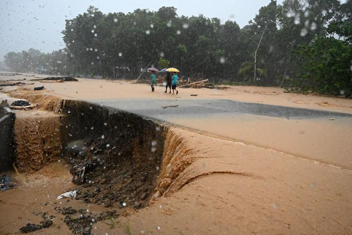 Men walk along a flooded road Wednesday in Toyos, Honduras, after heavy rains from Eta caused a river to overflow.