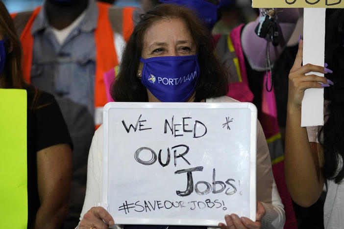 A woman holds a sign saying "We Need Our Jobs" during a protest by workers in the cruise ship industry in Miami last month. Employers added fewer jobs as pandemic cases start to surge again across the country.