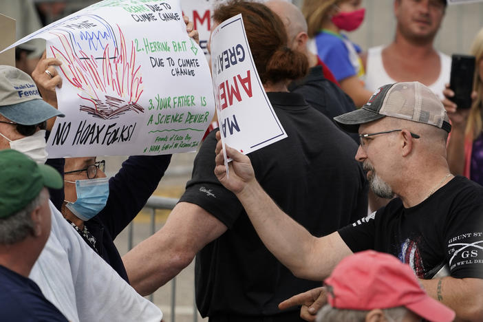 At a Saco, Maine, campaign rally for President Trump in September, a protester holding a sign detailing the effects of climate change on the Gulf of Maine (left) came face to face with Trump supporters who had different views.