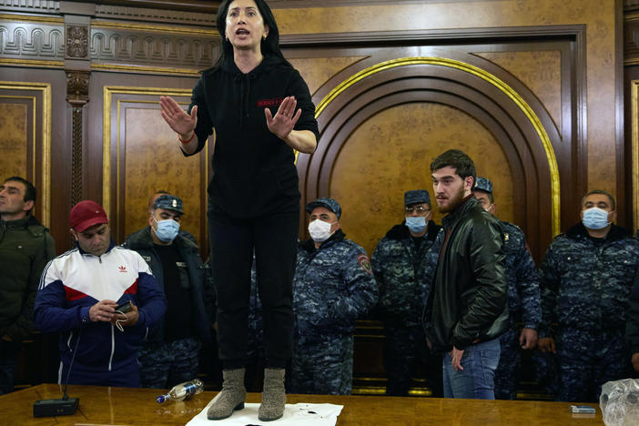 Police look on as a woman shouts among protesters who have stormed Armenian Prime Minister Nikol Pashinyan's office after the announcement of a peace deal in the war between Armenia and Azerbaijan on Tuesday.