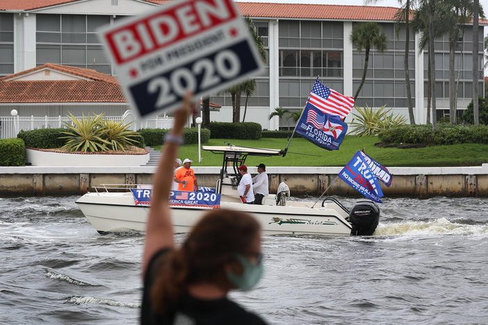 A person shows her support for Joe Biden as boaters pass by showing their support for President Donald Trump during a parade down the Intracoastal Waterway on Oct. 3, 2020 in Fort Lauderdale.