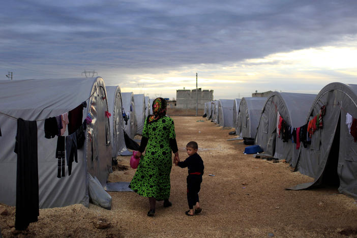 A Kurdish refugee mother and son from the Syrian town of Kobani walk beside their tent in a camp in the Turkish town of Suruc on the Turkish-Syrian border in 2014. President-elect Joe Biden aims to reverse the Trump administration's dramatic cuts to refugee admissions.