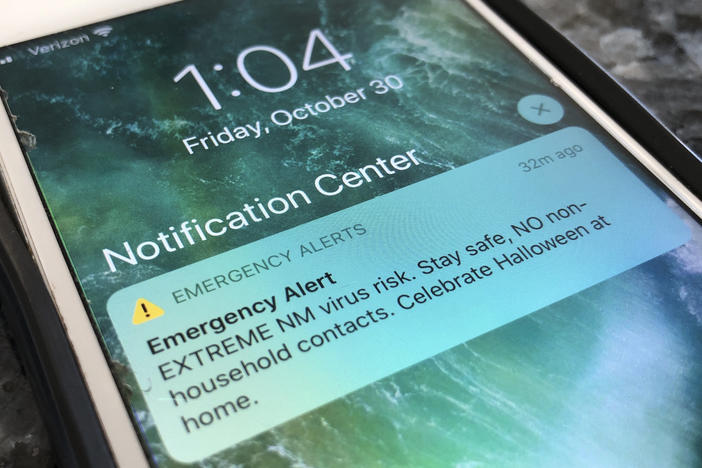 An emergency alert regarding the coronavirus pandemic is displayed on a cellphone Friday in Rio Rancho, N.M. The alert was sent out to New Mexicans across the state urging them to stay home amid a surge in COVID-19 cases and record-high hospitalizations.