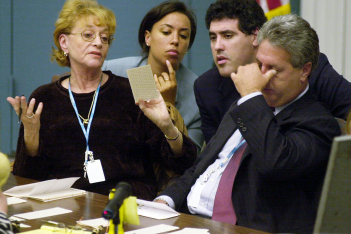Palm Beach County canvassing board chairman Judge Charles Burton rubs his eyes as board member Carol Roberts (left) shows a questionable ballot to the Democratic attorneys during the hand counting of ballots in West Palm Beach, Fla., on Nov. 22, 2000.