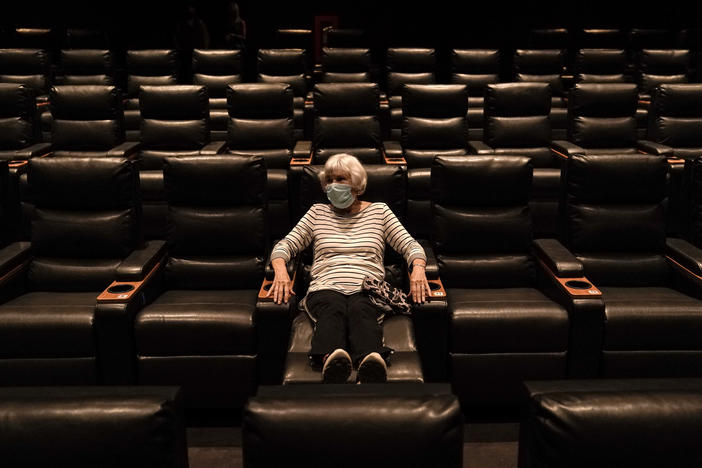 A woman sits in a theater in Irvine, Calif., waiting for a movie to start, on Sept. 8. A COVID-19 vaccine could unleash pent-up spending from households that have mostly avoided activities like going to the gym during the coronavirus pandemic.