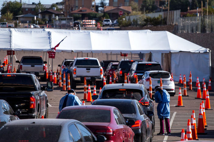 Medical workers wearing personal protective equipment register people in vehicles at a drive-through coronavirus testing site Monday in El Paso, Texas.