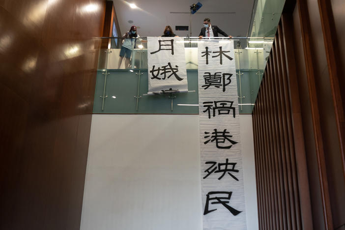 Pro-democracy lawmaker Lam Cheuk-ting hangs banners during a session at the Legislative Council outside of the main chamber on Thursday in Hong Kong. Fifteen pro-democracy lawmakers resigned en masse after four colleagues were disqualified from serving.