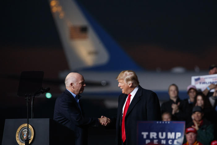Greg Gianforte, now Montana's Republican governor-elect, and President Donald Trump shake hands on stage during a campaign rally on Oct. 18, 2018, in Missoula, Mont.