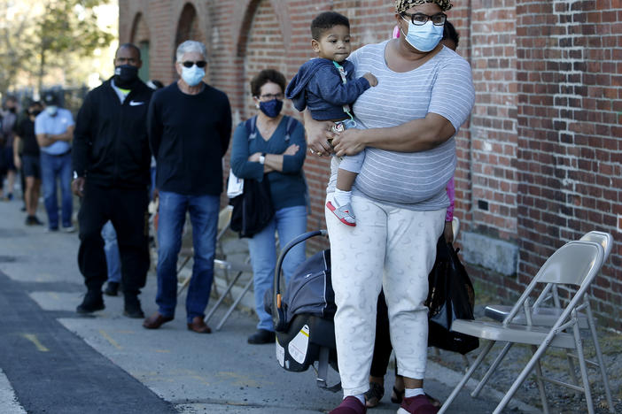 A woman holds her 1-year-old son as they wait in line to get a coronavirus test.