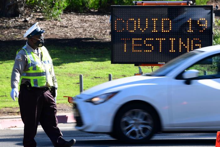 A traffic warden directs traffic as people arrive and depart from the coronavirus testing venue at Dodger Stadium in Los Angeles on Thursday.
