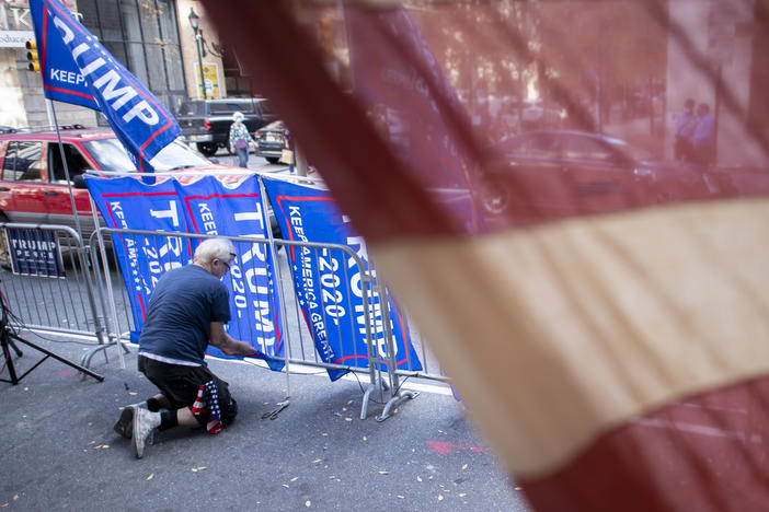 A supporter of President Trump fastens Trump campaign flags to a police barricade last week in Philadelphia.