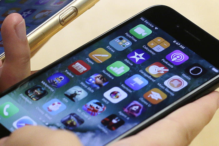 A customer compares her iPhone 6 (left) with an iPhone 7 at an Apple Store in Chicago. On Wednesday, more than 30 states announced a settlement with Apple over the company's past practice of slowing down a phone's battery.