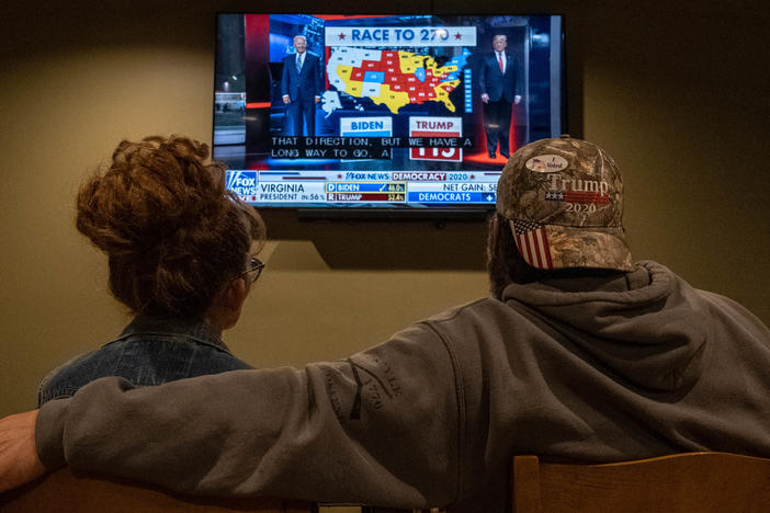 A couple watches the election results at a Republican watch party at Huron Valley Guns in New Hudson, Mich. People watching the results come in saw President Trump outperforming his position in preelection polls.
