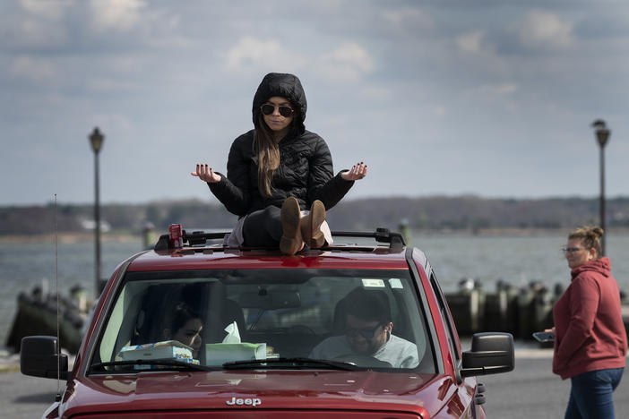 A member of Jesus' Church prays on top of a car during a Sunday church service held at Great Marsh Park in Cambridge, Maryland, on March 22, 2020.