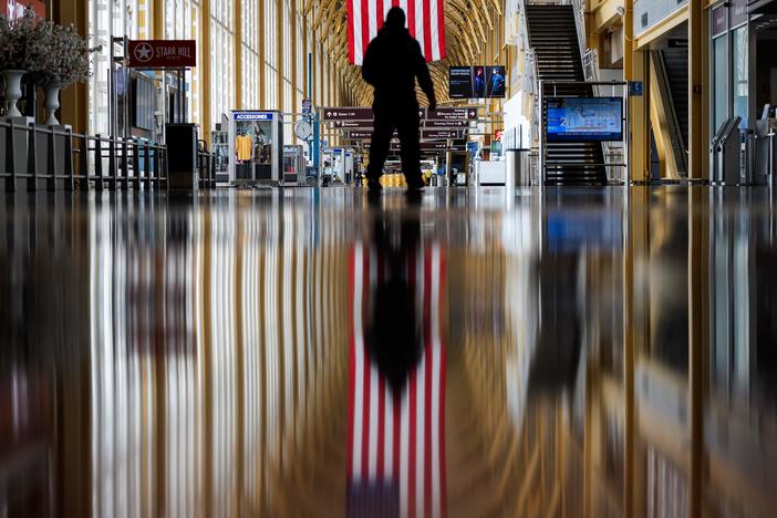 An airport employee walks through Reagan National Airport in Arlington, Va., earlier this year. On Thursday, the Centers for Disease Control and Prevention warned that Americans should refrain from traveling for the upcoming holiday.