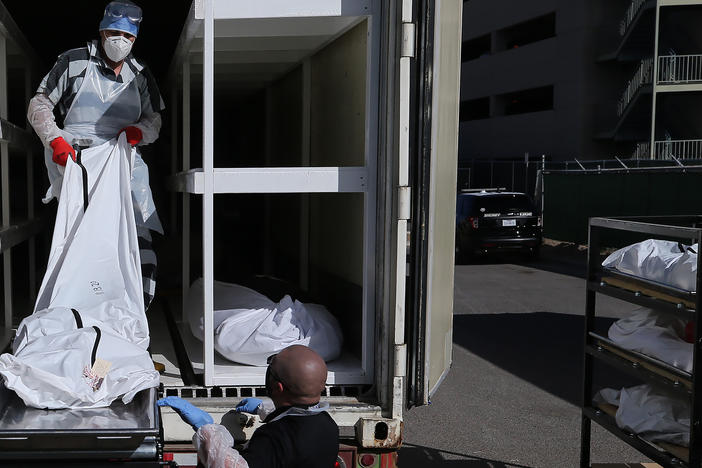 A low-level inmate from El Paso County detention facility works loading bodies wrapped in plastic into a refrigerated temporary morgue trailer in a parking lot of the El Paso County Medical Examiner's office on Tuesday.