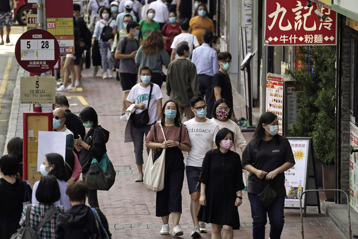 In this Oct. 9, 2020, photo, people walk down a street in Hong Kong. Singapore and Hong Kong have postponed a planned air travel bubble meant to boost tourism amid a spike in coronavirus infections in Hong Kong.