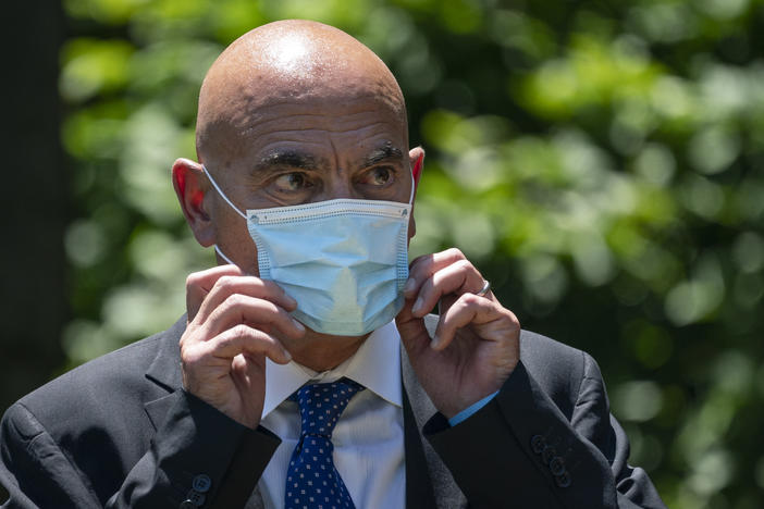 Moncef Slaoui, chief scientific adviser for Operation Warp Speed, listens as President Trump delivers remarks about coronavirus vaccine development in the Rose Garden on May 15. Slaoui says Americans could start seeing a vaccine by the middle of December.