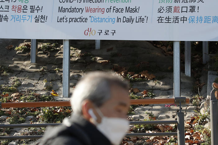 A man wearing a face mask walks past a banner showing precautions against the coronavirus in Seoul on Monday.