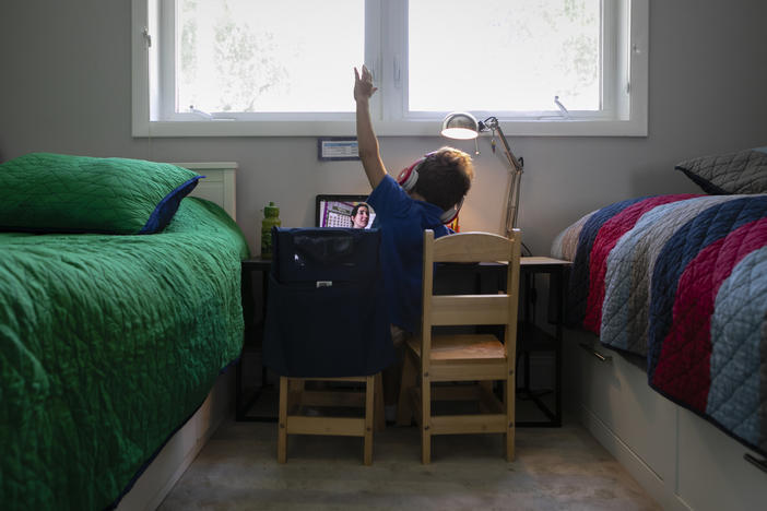 A student raises his hand while attending an online class from home in Miami on Sept. 3.