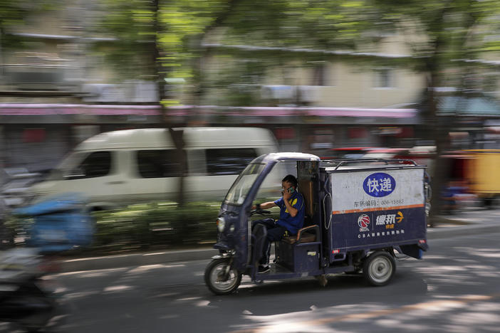A private delivery company's courier drives his delivery vehicle in a residential area in Beijing in June.
