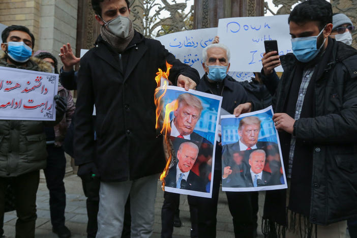 Iranian protesters burn images of President Trump and President-elect Joe Biden during a rally Saturday in  Tehran. Iranian leaders have blamed Israel and its close ally, the U.S., for the assassination of a top Iranian nuclear scientist.