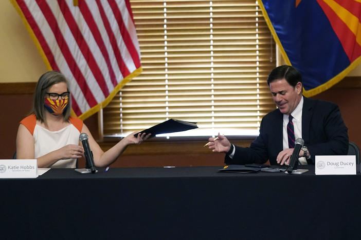 Arizona Secretary of State Katie Hobbs and Gov. Doug Ducey exchange election documents as they certify election results Monday at the Arizona Capitol in Phoenix.