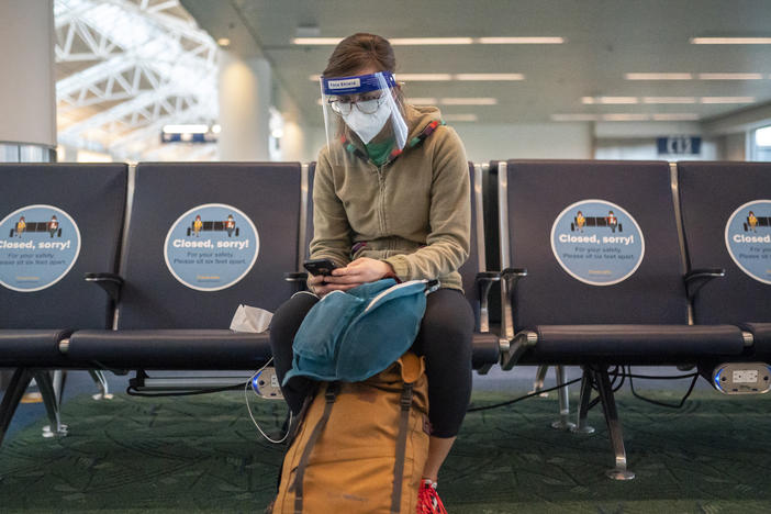 A traveler waits for a flight at Portland International Airport in Oregon last week. Public health experts say it's important that people who traveled or gathered with others are especially careful over the next two weeks.