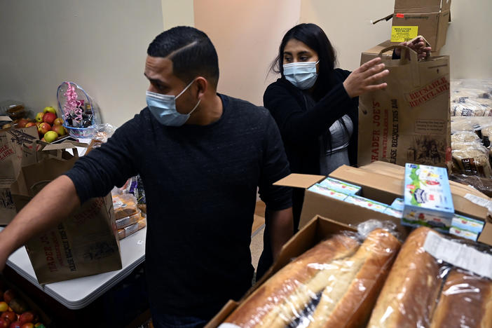 Ingmar Riveros and Peruvian refugee Xiomy De la Cruz distribute food from a store basement last month in Hartford, Conn.
