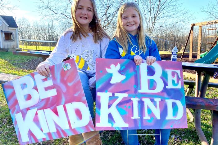 On a November afternoon sisters Raegan and Rylyn Richins sit at their picnic table in their backyard in a Kentucky county holding signs they just painted.