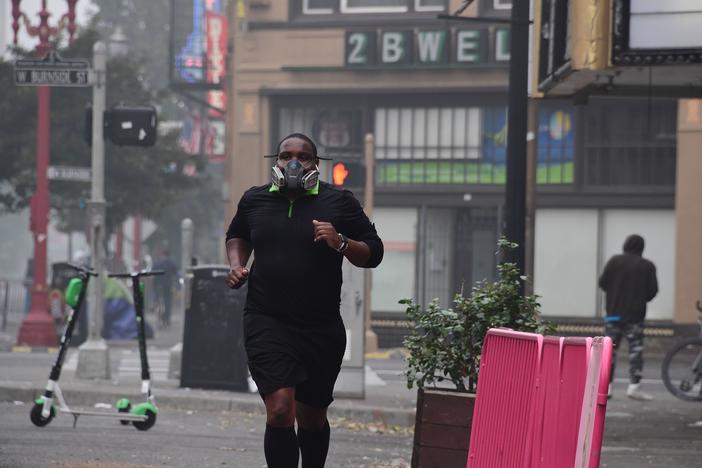 A Portland, Ore., resident wears a respirator to protect himself from wildfire smoke as he jogs in downtown in September 2020.