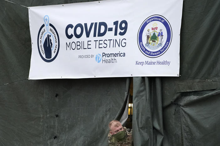 A member of the National Guard assisting at a COVID-19 mobile testing location looks out of a tent used for drive-thru tests earlier this month in Auburn, Maine.