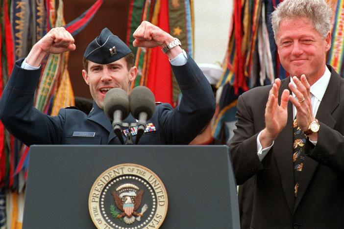 President Bill Clinton applauds Air Force pilot Scott O'Grady, who was shot down in Bosnia and survived six days in the woods, in 1995. Now a Trump supporter and tapped for a top Pentagon job, O'Grady has been endorsing baseless conspiracy theories related to the election.