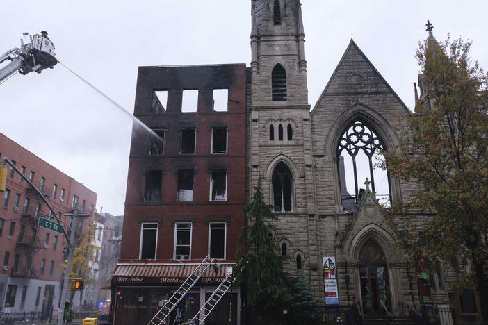 Firefighters work to extinguish a fire erupted from the building next to Middle Collegiate Church on Saturday. The historic church in lower Manhattan was gutted by a massive fire early Saturday that sent flames shooting through the roof.