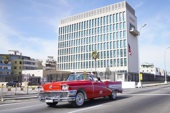 A car drives past the U.S. Embassy in Havana in 2019. Dozens of Americans working at U.S. diplomatic missions in Cuba and China in recent years have suffered from ailments that have included headaches, balance problems and memory loss.
